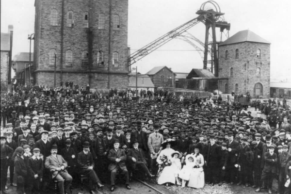 The photograph shows a large group of workmen around Major David Davies, later Lord Davies of Llandinam, chairman of the Ocean Coal Company, together with members of his family during a VIP visit to Treharris pit