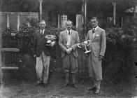 Three men holding trophies