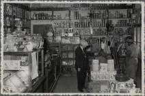 2 postcards, 1 shows the interior of a shop,...