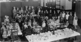 Group of adults and children at a tea party in...