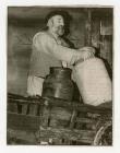 Photograph of man with milk churns in cart